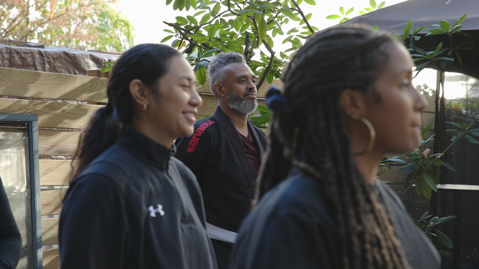 Jiu-jitsu students lined up outdoors with a man in a black gi behind them, from the Jons Dojo documentary