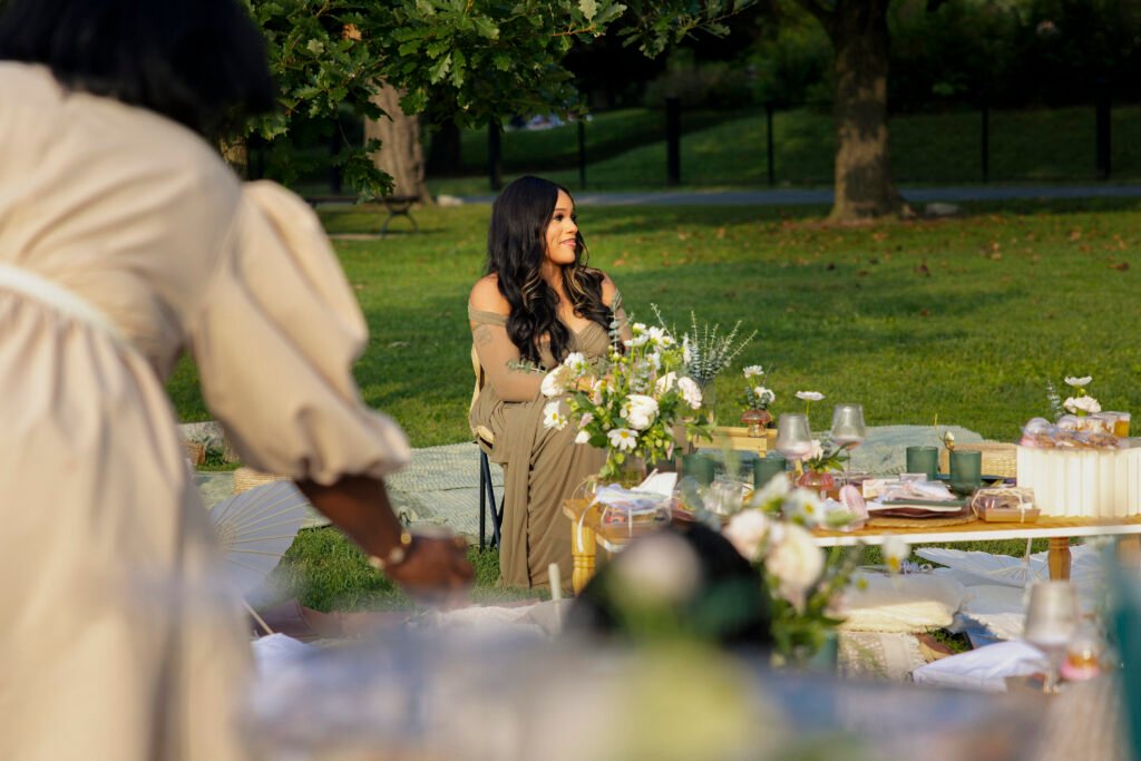 Mother-to-be seated at a flower-filled picnic table in golden-hour light during a Mother’s Blessing hosted by The Christian Doula Experience