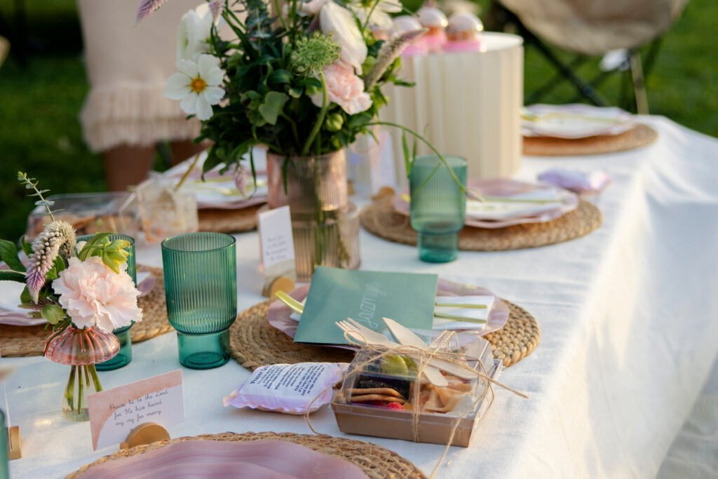 Picnic table set with fresh flowers, green glassware, woven placemats and scripture cards at the Mother’s Blessing hosted by The Christian Doula Experience