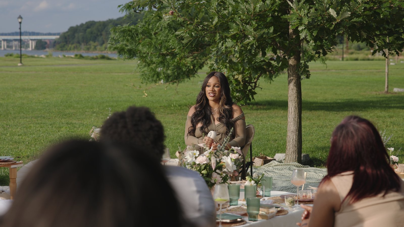 Mother-to-be speaking to guests at an outdoor Mother’s Blessing picnic by the river, hosted by The Christian Doula Experience